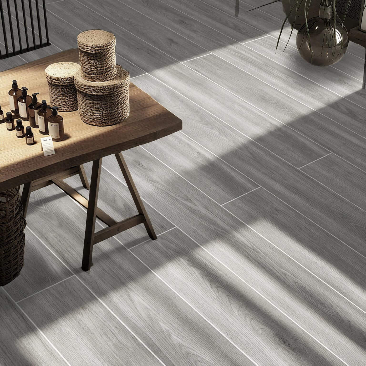 A bright, chic boutique setting where the Effortless Weathered Wood Look Tile provides a light and airy foundation, complementing a rustic wooden table and creating a welcoming, coastal ambiance.