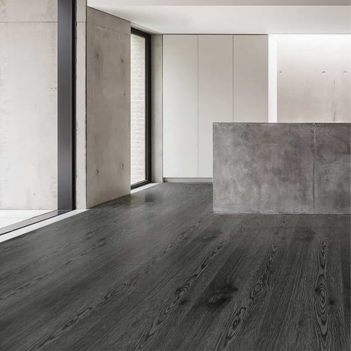 Urban Industrial Graphite Ash Wood Look LVT Flooring in a modern kitchen, capturing the raw, edgy feel of an industrial loft. This 100% waterproof LVT resists scratches, stains, and dents, providing a powerful, sophisticated, and effortless to clean backdrop.