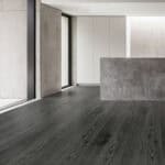Urban Industrial Graphite Ash Wood Look LVT Flooring in a modern kitchen, capturing the raw, edgy feel of an industrial loft. This 100% waterproof LVT resists scratches, stains, and dents, providing a powerful, sophisticated, and effortless to clean backdrop.