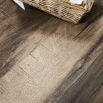 Close-up of Rustic Smoked Brown Wood Look Tile on a bathroom floor, showcasing its smoky tones and deep grain. This 100% waterproof porcelain tile offers unmatched performance, resisting scratches and stains for enduring rustic style.