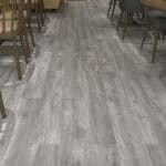 Proven Modern Ash Grey Wood Look SPC in a stylish cafe setting with dark wood furniture.