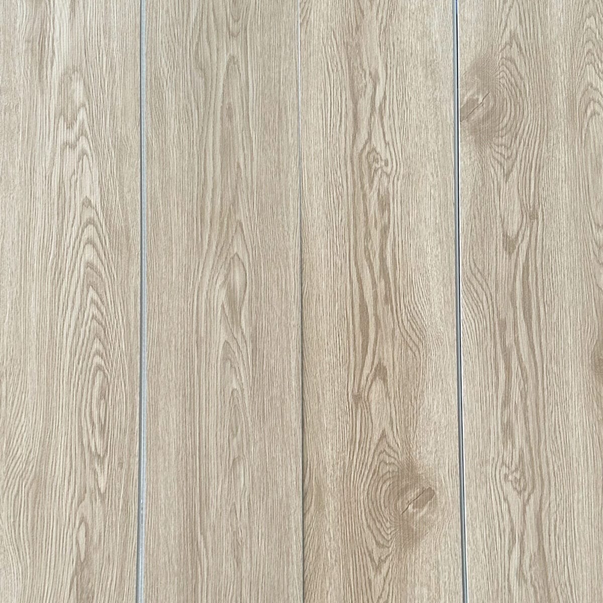 Real-world photograph of Serene Coastal Beige Oak SPC planks laid together, showcasing their seamless, natural wood appearance.