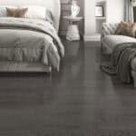 Ultimate Chic Charcoal Oak flooring in a luxurious bedroom with a white tufted chaise lounge and modern furniture.