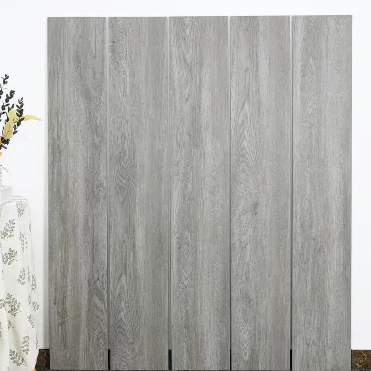 Real photo of Effortless Weathered Wood Look Tile planks, showcasing their light gray, sun-bleached coastal wood grain.