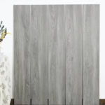 Real photo of Effortless Weathered Wood Look Tile planks, showcasing their light gray, sun-bleached coastal wood grain.